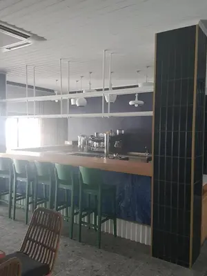 a kitchen with a bar with green chairs in a room at E.J. Pyrgos Bay Hotel in Kato Pyrgos