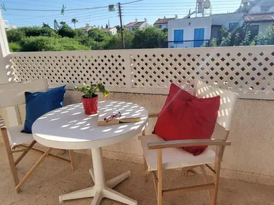 a table and chairs on a balcony with a table and pillows at Protaras Happy Sunny Holidays in Paralimni