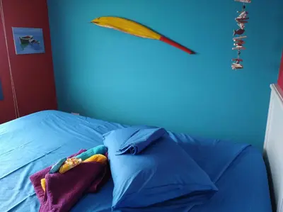 a blue bed with pillows and a wooden spear on the wall at Il Mare in Larnaka