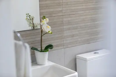 a white flower in a white vase on a sink in a bathroom at Mackenzie Zoe Seafront Suite in Larnaka