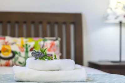 a stack of towels with a flower on a bed at Protaras Palm Suite in Protaras