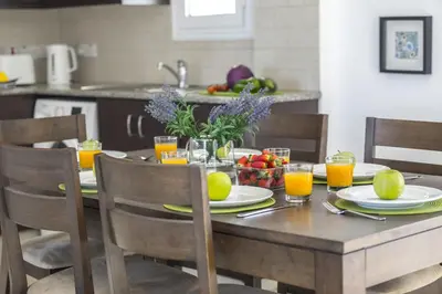 a wooden table with plates of fruit and glasses of orange juice at Protaras Palm Suite in Protaras