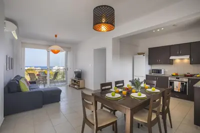 a kitchen and living room with a table and chairs at Protaras Palm Suite in Protaras