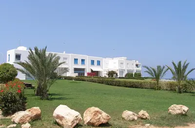 a large white house with rocks in front of it at Luxury Bay View Villa 28 Right On The Beach in Protaras