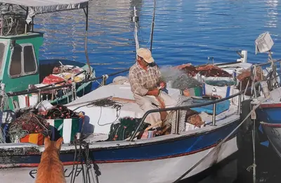 a man sitting on a boat in the water with a dog at Poseidon Boutique Apartment 1 in Limassol