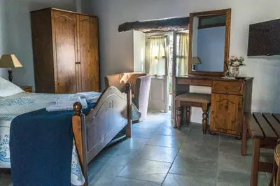 a bedroom with a bed and a dresser and a desk at To Konatzi tou Flokka in Ayios Theodhoros