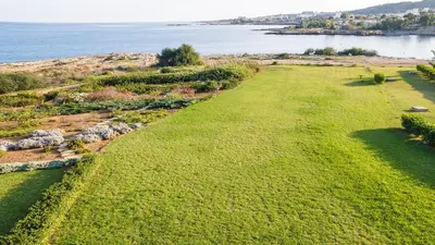 an aerial view of a field of grass next to the water at Luxury Bay View Villa 20 Right On Τhe Beach in Protaras