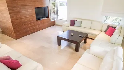 a living room with white couches and a tv at Luxury Bay View Villa 20 Right On Τhe Beach in Protaras