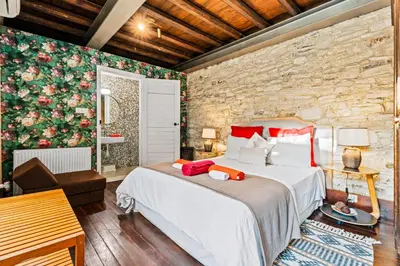 a bedroom with a large bed and a stone wall at RedBlue Door Two Traditional Listed Houses in Pano Lefkara