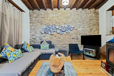 a living room with a couch and a stone wall at RedBlue Door Two Traditional Listed Houses in Pano Lefkara