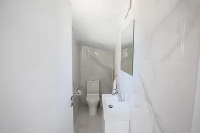 a white bathroom with a toilet and a sink at Jason Villas in Protaras