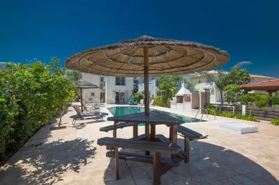 a table with an umbrella next to a pool at Jason Villas in Protaras