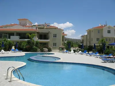 a swimming pool in a resort with chairs and a building at Pyla Gardens A102 in Pyla