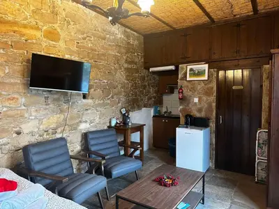 a living room with two chairs and a table and a television at Pachna Studios - Village Life in Limassol