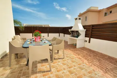 a patio with a table and chairs on a balcony at Nissi Villa Crystal in Ayia Napa