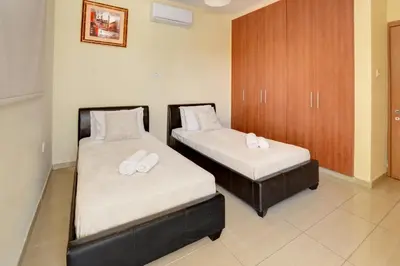 two beds in a hotel room with white sheets at Nissi Villa Crystal in Ayia Napa