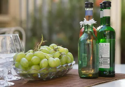 two bottles of wine and a bowl of grapes on a table at Sunny Family Home By The Beach in Limassol