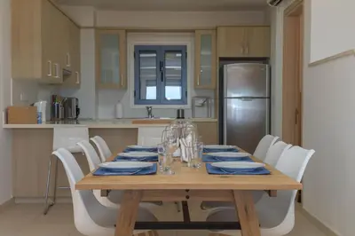 a kitchen with a wooden table and white chairs at Indigo in Protaras