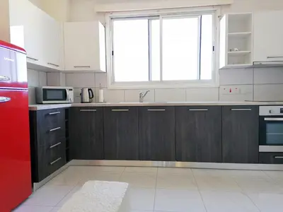 a kitchen with wooden cabinets and a red refrigerator at Sandy Beach Complex in Pervolia