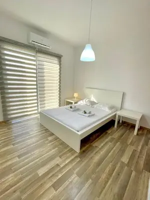 a bedroom with a white bed and a wooden floor at Sandy Beach Complex in Pervolia