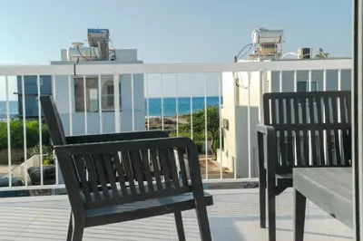 two black benches sitting on a balcony overlooking the ocean at Sandy Beach Complex in Pervolia