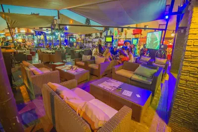 a restaurant with tables and chairs and people playing video games at Windmills Hotel Apartments in Protaras