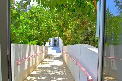 a hallway with a white fence and trees at Napian Suites in Ayia Napa