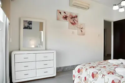 a bedroom with a bed and a dresser and a mirror at Beach Front Bella Vista by Ezoria Villas in Protaras