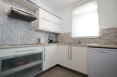 a kitchen with white cabinets and a sink and a window at Beach Front Bella Vista by Ezoria Villas in Protaras