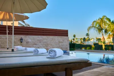 a group of towels sitting on a bed next to a swimming pool at Beach Front Bella Vista by Ezoria Villas in Protaras