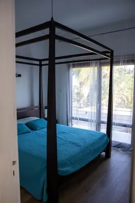 a bedroom with a canopy bed with blue sheets and a window at Balinese in Ayia Napa