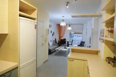 a kitchen with a refrigerator and a living room at Bianco E U Apartment in Nicosia