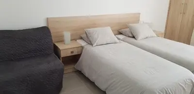 a hotel room with two beds and a chair at Sunny Napa Apartments in Ayia Napa