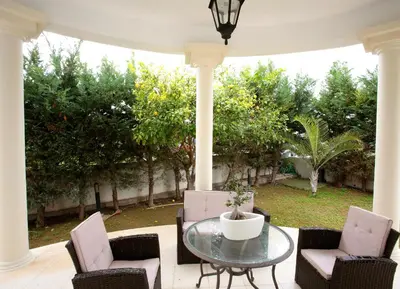 a patio with a table and chairs and trees at The White House in Larnaka