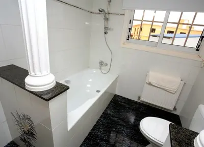 a white bathroom with a tub and a toilet at The White House in Larnaka