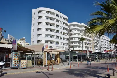 a white building on a city street with palm trees at Kolonaki Seaview Apartments in Larnaka
