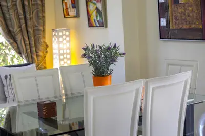 a glass table with white chairs and a plant on it at Ayia Napa Tropical Beach Villa in Ayia Napa