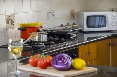 a kitchen with a stove with tomatoes and a glass of wine at Ayia Napa Tropical Beach Villa in Ayia Napa