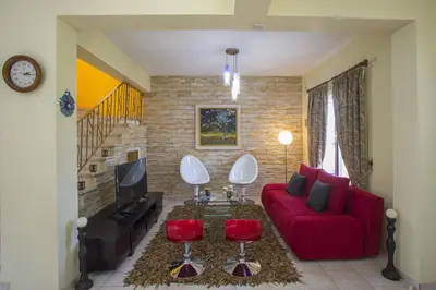 a living room with a red couch and two red chairs at Ayia Napa Tropical Beach Villa in Ayia Napa