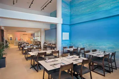 a restaurant with tables and chairs and a blue wall at Okeanos Beach Boutique Hotel in Ayia Napa