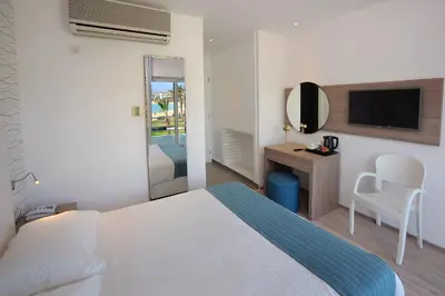 a bedroom with a bed and a desk and a tv at Okeanos Beach Boutique Hotel in Ayia Napa
