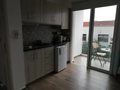 a kitchen with wooden cabinets and a sliding glass door at Chicos Studios in Ayia Napa