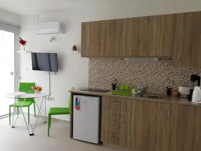 a kitchen with wooden cabinets and a table and a refrigerator at Chicos Studios in Ayia Napa