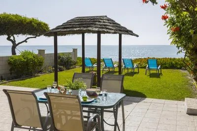 a table and chairs with an umbrella and the ocean at Meneou Beachfront Villa in Meneou