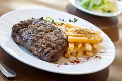 a plate of food with a steak and french fries at Semeli Hotel in Nicosia