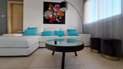 a living room with a white couch and a table at Million flowers in Protaras