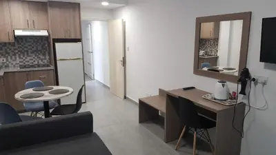 a living room with a table and a kitchen at Manoli Apartments in Ayia Napa