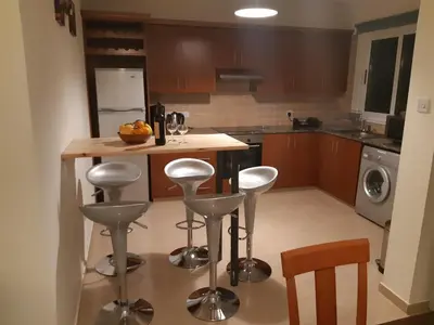 a kitchen with a island with bar stools at Vasilas Holiday Apartment #1 in Larnaka