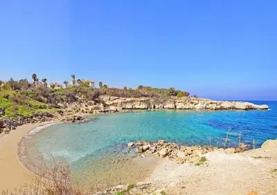 a beach with blue water and a rocky island at Phaedrus Living: Seaside Luxury Villa Anafi in Paralimni