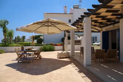 a patio with a table and an umbrella at Phaedrus Living: Seaside Luxury Villa Anafi in Paralimni